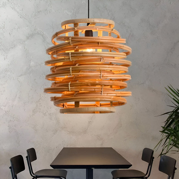 Une lampe design en rotin tressé à la main. La lumière diffuse une lueur chaleureuse et tamisée à travers les interstices du rotin. La lampe est suspendue au plafond par un fil électrique noir. TO-0859804577,TO-2760119130,