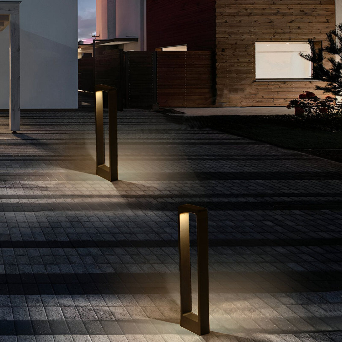 Deux lampadaires modernes en forme de rectangle émettent une lumière chaude sur un chemin en pierre. NE-755254144X,NE-2769874705,NE-0294437452,NE-1666104728,NE-5327672107,NE-988439248X,NE-8976410963,NE-906375275X,