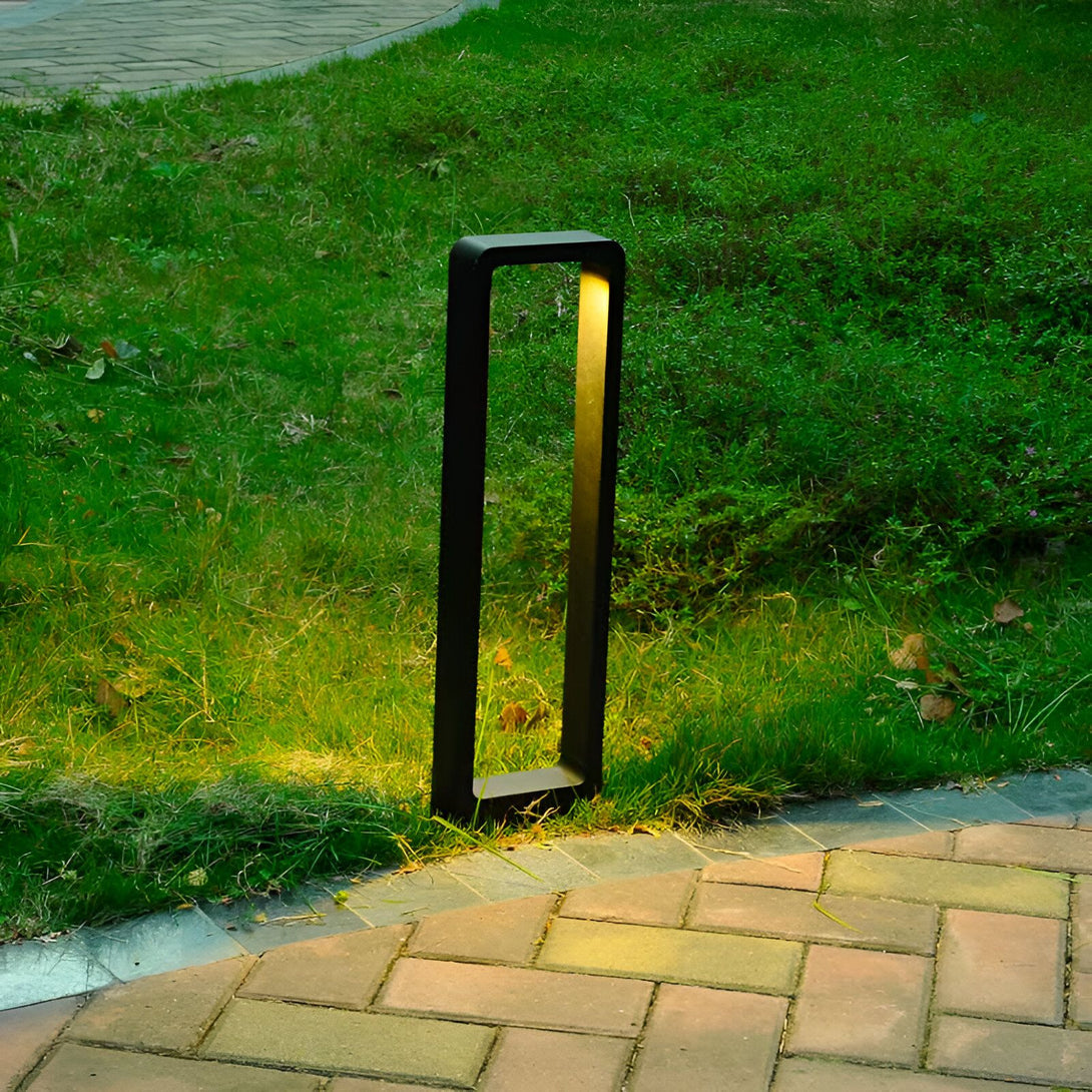 Une image d'une lampe de jardin noire et rectangulaire. La lampe est posée sur l'herbe et émet une lumière jaune. NE-755254144X,NE-2769874705,NE-0294437452,NE-1666104728,NE-5327672107,NE-988439248X,NE-8976410963,NE-906375275X,