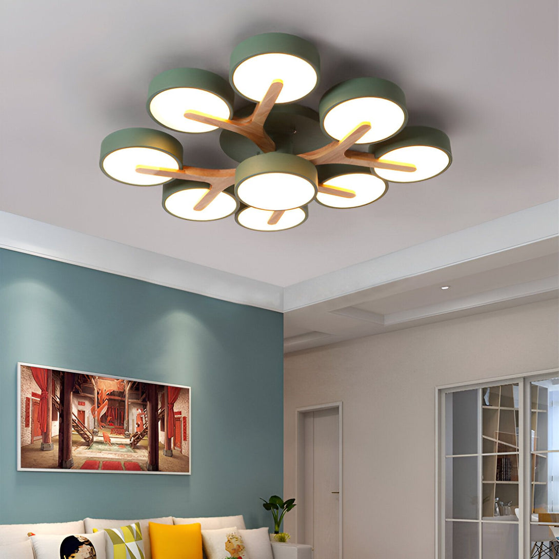 Un plafonnier LED vert en forme de branche d'arbre avec des feuilles rondes en bois clair. Il est fixé au plafond et éclaire le salon. PL-2355612153,PL-5660108733,PL-3743409283,PL-6047112455,PL-2411414536,PL-2840750430,