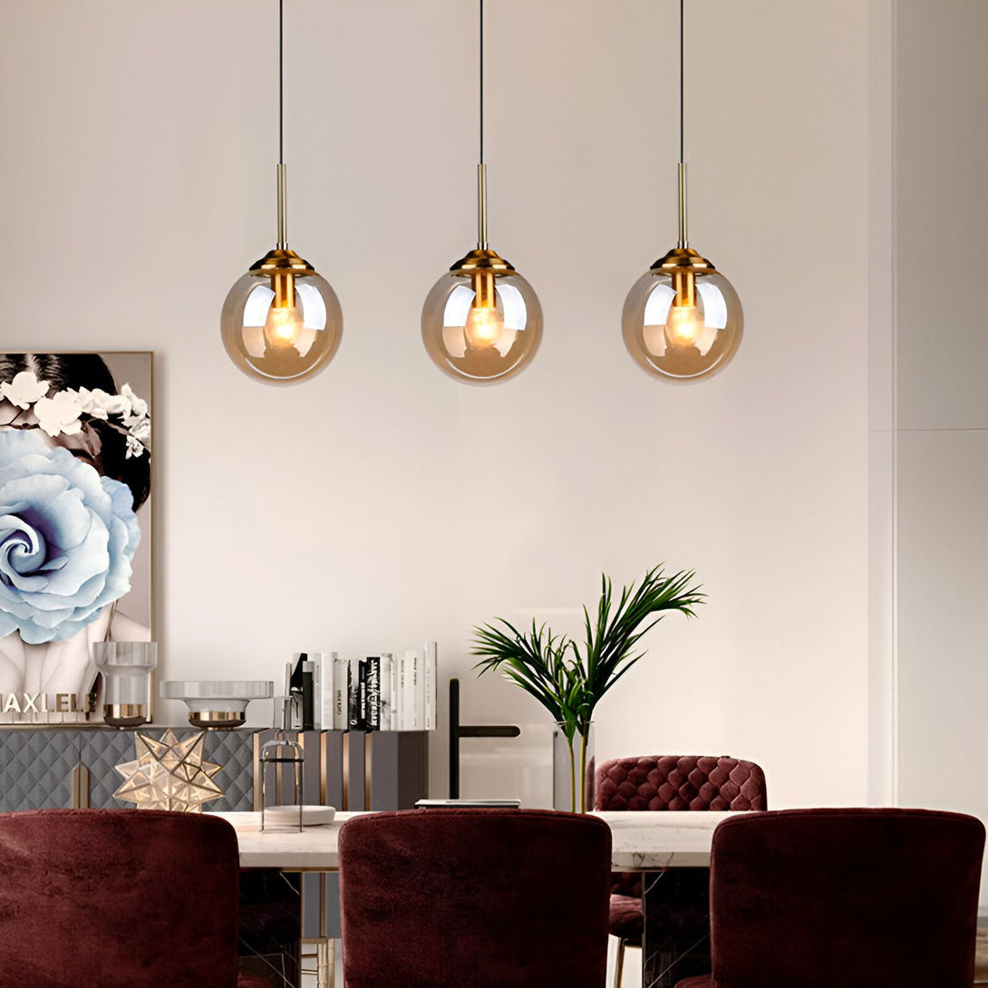 Une image d'un luminaire moderne en verre. Il est de couleur marron et a une forme de boule. Il est suspendu au plafond par un fil doré. Il y a trois luminaires sur l'image. VE-8794649839,VE-2128730597,VE-1613731329,VE-1755348045,VE-9817635031,VE-7370967131,