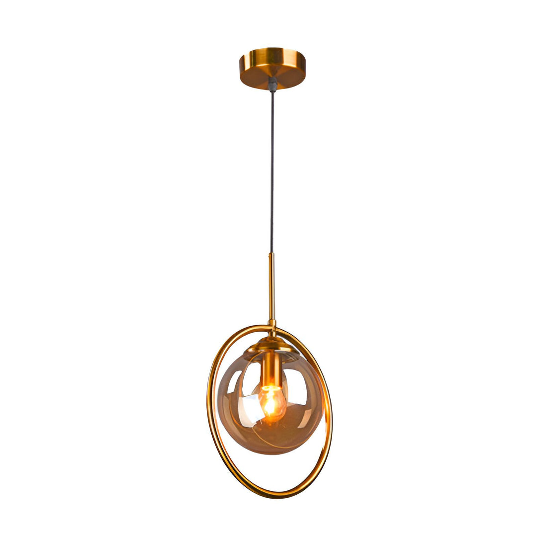 Une lampe suspendue en métal doré avec une sphère en verre fumé. La lumière est allumée et diffuse une lumière chaude et tamisée. Le luminaire est suspendu par un fil noir. VE-8794649839,VE-2128730597,VE-1613731329,VE-1755348045,VE-9817635031,VE-7370967131,