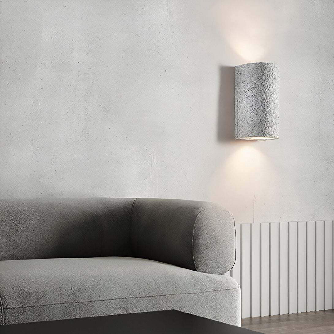 Une image d'un salon avec un canapé gris et une applique murale en pierre. NA-3923317158,NA-6067964244,NA-3358865746,NA-2876745291,NA-6391241465,