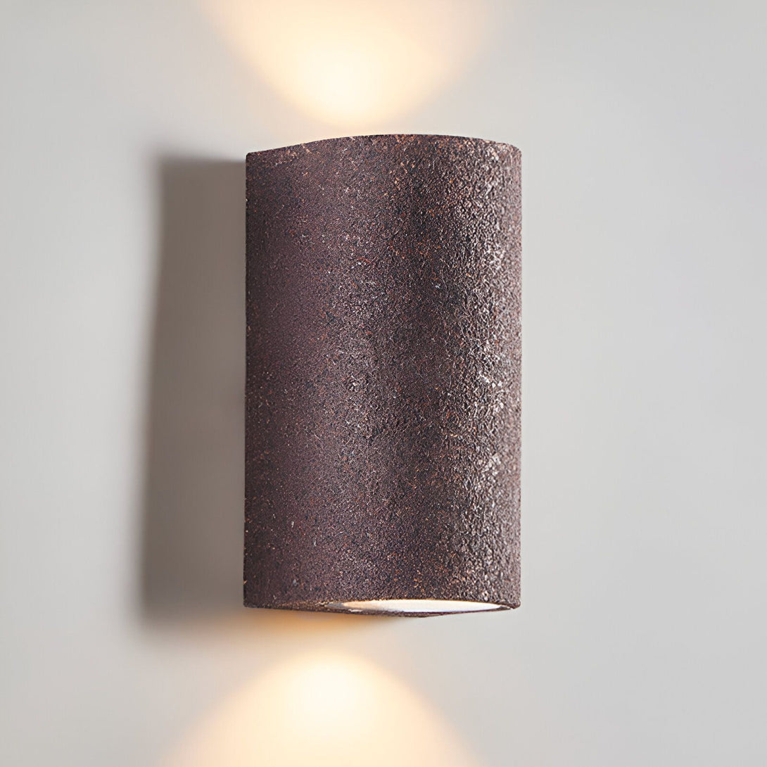 Une applique murale en forme de cylindre, de couleur marron, avec une lumière qui brille vers le haut et le bas. NA-3923317158,NA-6067964244,NA-3358865746,NA-2876745291,NA-6391241465,