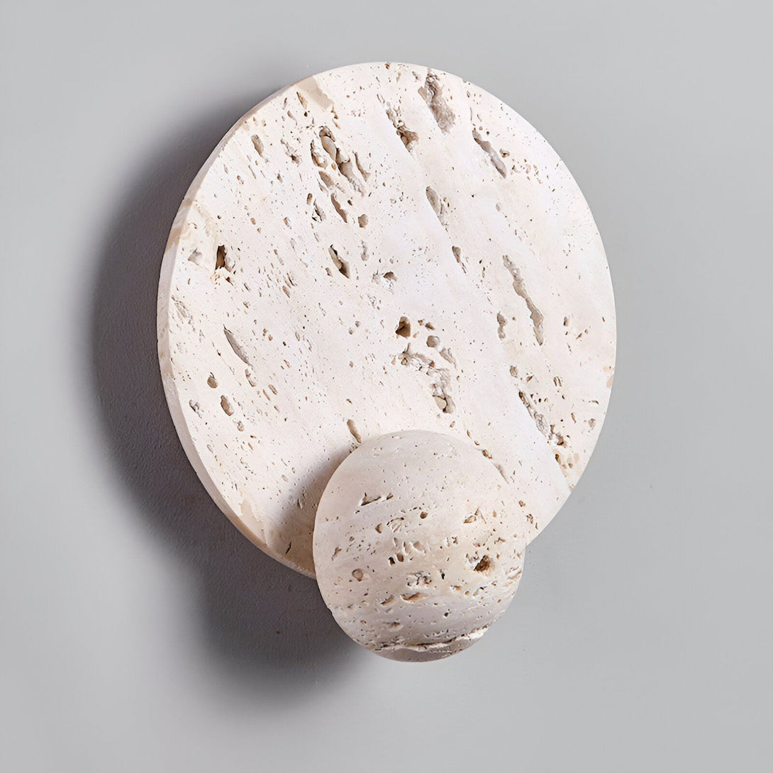 Une image d'une applique murale en pierre beige avec une forme ronde et une petite boule en pierre beige qui pend en dessous. PI-3050710888,