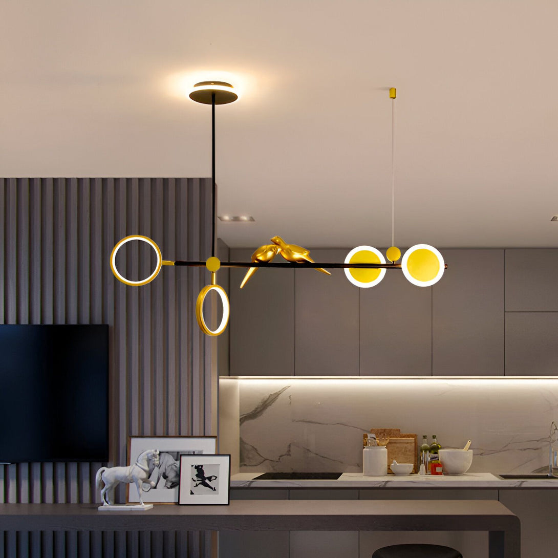 Une image d'une suspension oiseau moderne en métal doré avec des cercles en métal doré et des LED intégrées. La suspension est accrochée au plafond et éclaire la pièce. OS-708742372X,OS-509121187X,