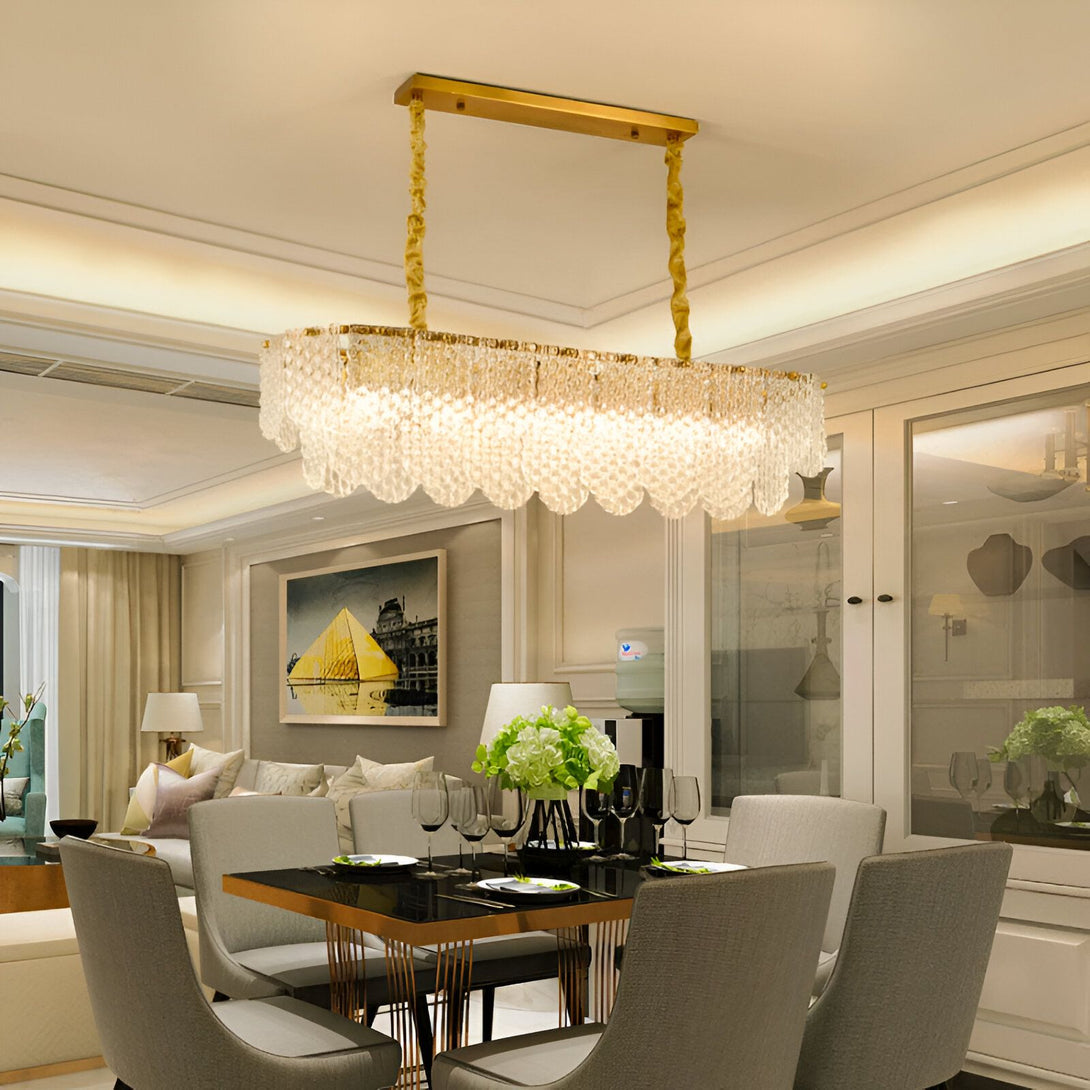 Une image d'un lustre en cristal doré suspendu au plafond d'une salle à manger. La table à manger est en verre noir et les chaises sont en tissu gris. Il y a un buffet en bois blanc dans le coin de la pièce. PE-8989591325,PE-642660481X,PE-3701985286,PE-234610650X,PE-4491396426,PE-9917021671,