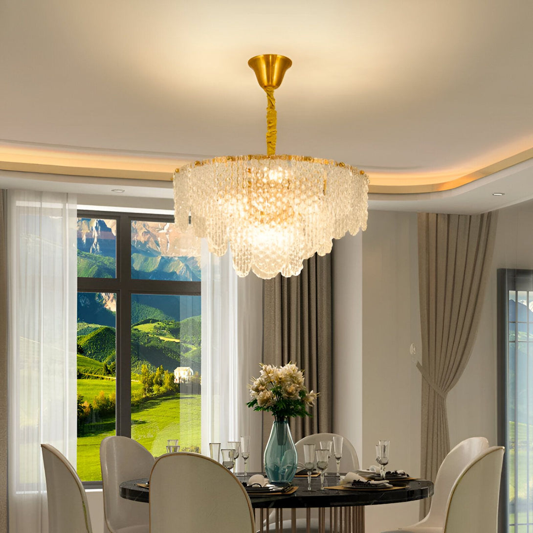 Une image d'un lustre en cristal doré suspendu au plafond d'une salle à manger. La pièce est dotée de grandes fenêtres et de rideaux blancs. Il y a une table à manger ronde avec des chaises et un vase avec des fleurs au centre. PE-8989591325,PE-642660481X,PE-3701985286,PE-234610650X,PE-4491396426,PE-9917021671,