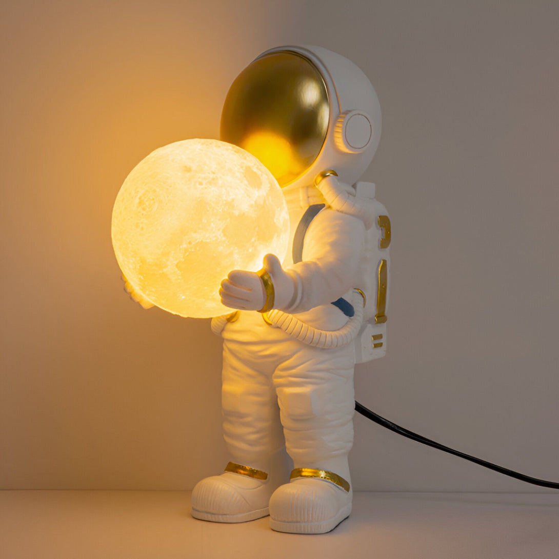 L'image représente une figurine d'astronaute tenant une lune lumineuse dans sa main. La figurine est blanche et dorée, et la lune est jaune. La figurine est posée sur une surface blanche. AS-8040619378,AS-6297617716,AS-985749658X,AS-5146813485,AS-467019237X,AS-1270289780,AS-9299916284,AS-1323225196,AS-8179455408,AS-9057229498,AS-5184569901,AS-6777445285,AS-3281223907,AS-2399785142,AS-3426277867,AS-2500196445,