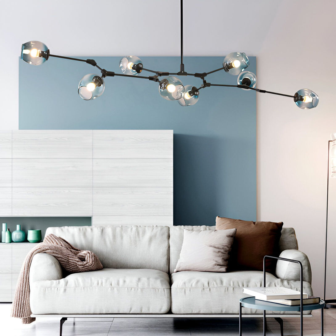 Une image d'un salon avec un canapé blanc et une table basse. Il y a une grande lampe noire au plafond avec des boules en verre bleu clair. Le mur du fond est peint en bleu foncé et il y a un meuble TV blanc.