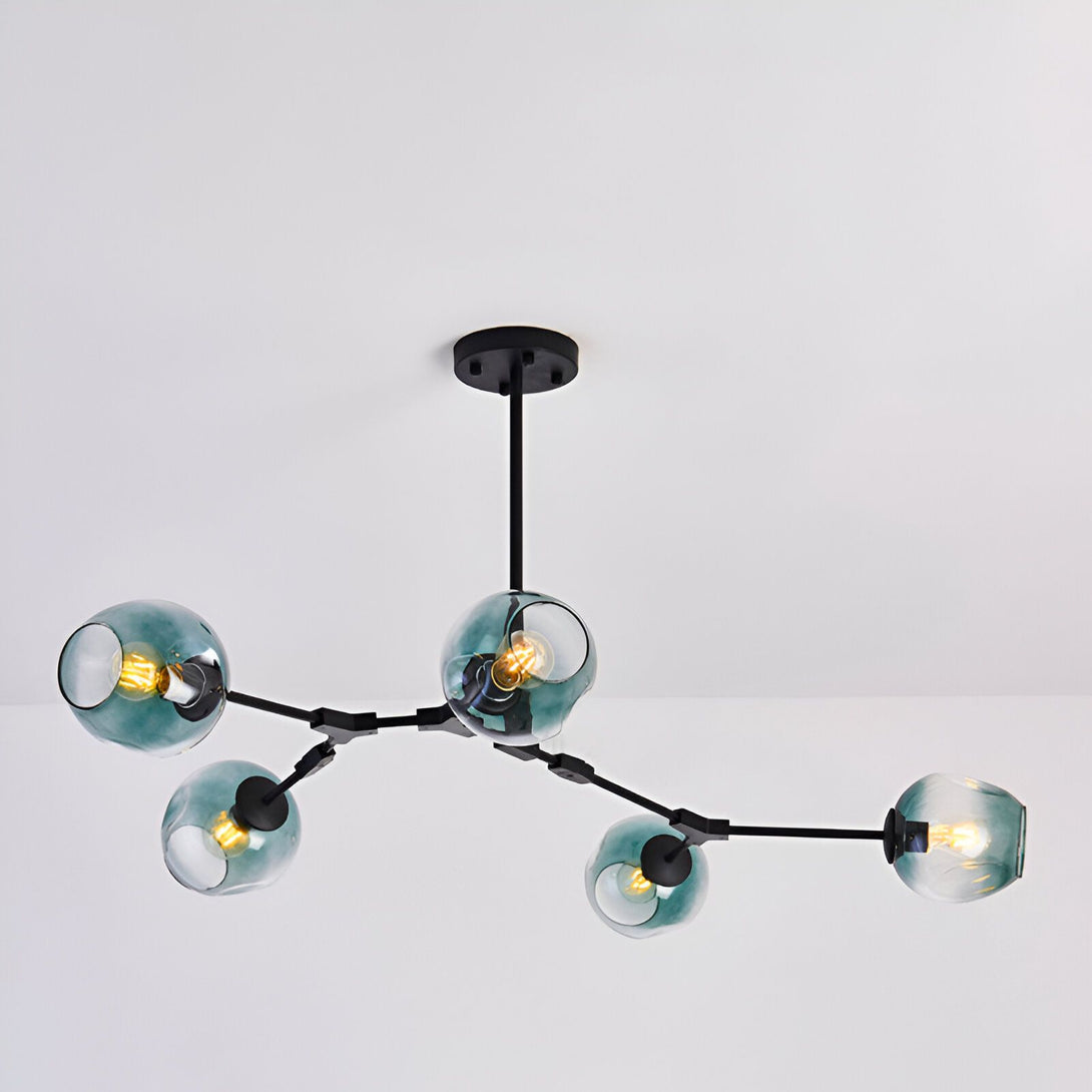 L'image montre un lustre moderne avec cinq globes en verre soufflé de couleur bleu-vert. Le lustre est suspendu au plafond par une tige en métal noir.