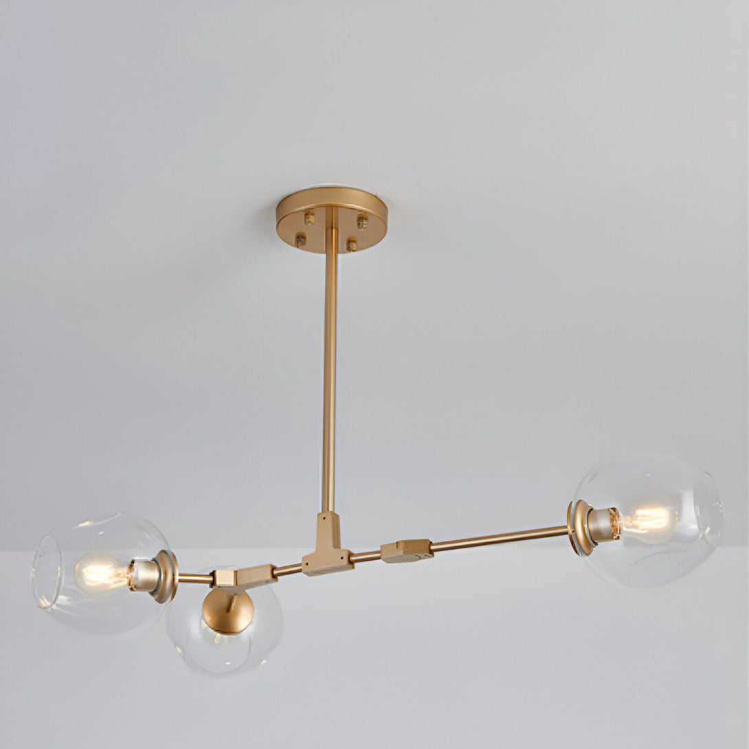 Une image d'un plafonnier doré à trois branches avec des globes en verre transparent.