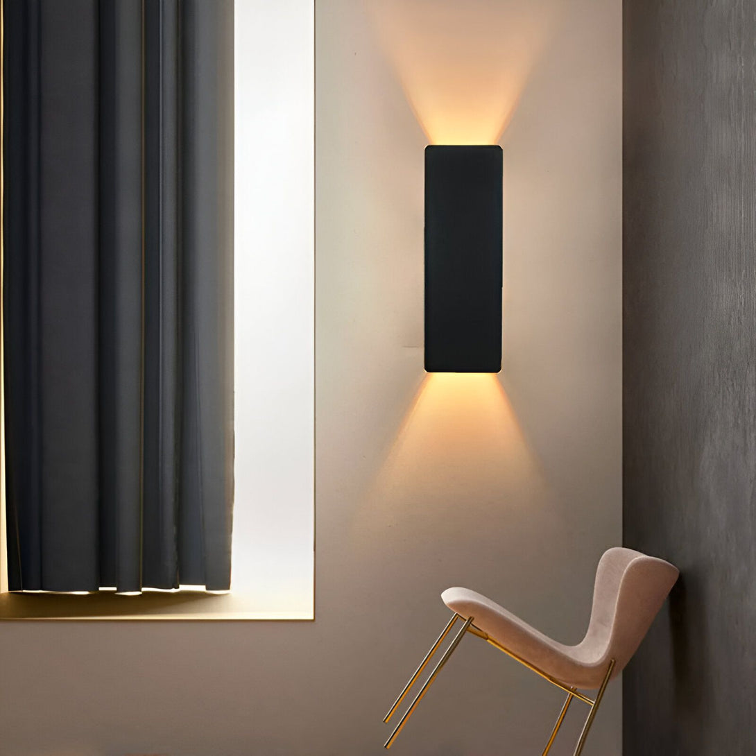 Une image d'un luminaire salle de bain applique. Le luminaire est de couleur noire et de forme rectangulaire. Il est fixé au mur et émet une lumière chaude et diffuse. À côté, se trouve un fauteuil rose et beige, et des rideaux gris. TY-7033508808,TY-8211956470,TY-964686211X,TY-5755994811,TY-9769370177,TY-6844157703,TY-726779890X,TY-9707577746,