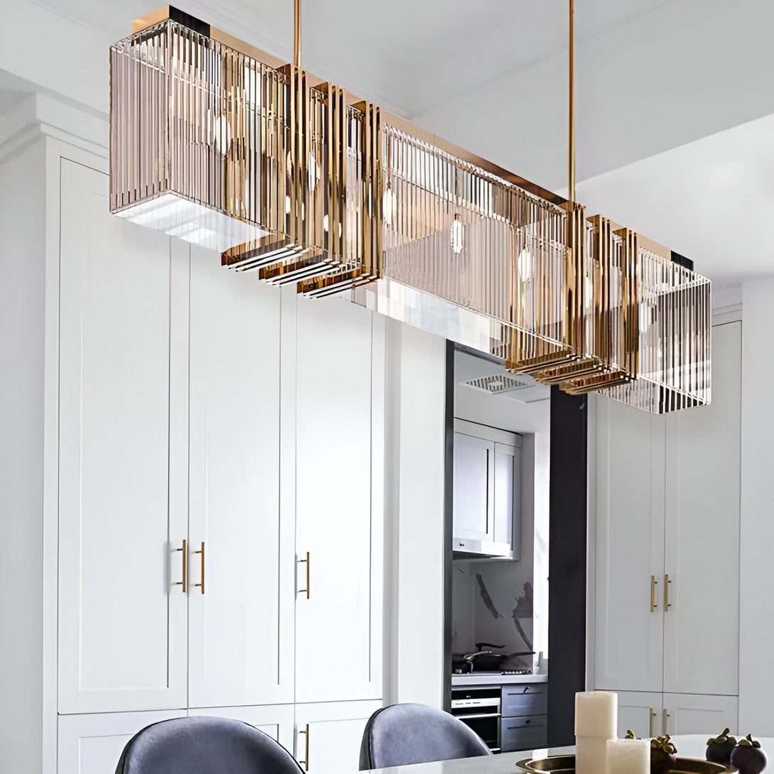 Une image d'un lustre en cristal doré suspendu au plafond. Le lustre est de forme rectangulaire et est composé de plusieurs tubes de cristal transparents. Il est suspendu par des câbles métalliques fins et est éclairé par des ampoules LED. RE-6447629544,RE-1964704464,RE-6866198763,RE-6225987975,RE-0401398579,RE-3333424606,RE-0629353603,RE-8827981071,