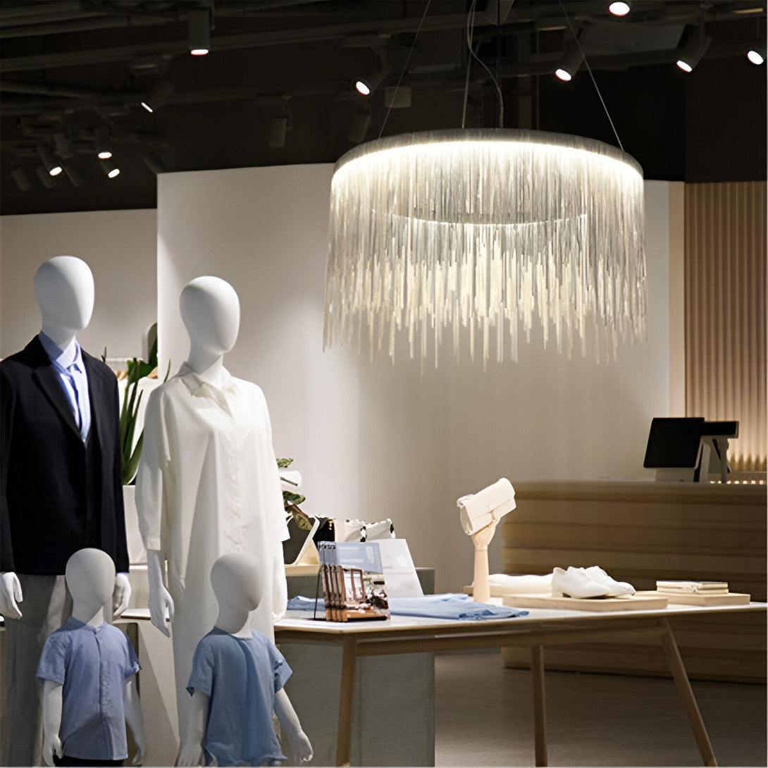 Une image d'un lustre en acier brossé et en aluminium. Le lustre est suspendu au plafond et est composé de plusieurs anneaux concentriques en acier brossé et en aluminium. Les anneaux sont reliés entre eux par des fils métalliques fins qui créent un effet de cascade. Le lustre est éclairé par des LED qui diffusent une lumière douce et tamisée. VA-9669156378,VA-3706166739,VA-0973338423,