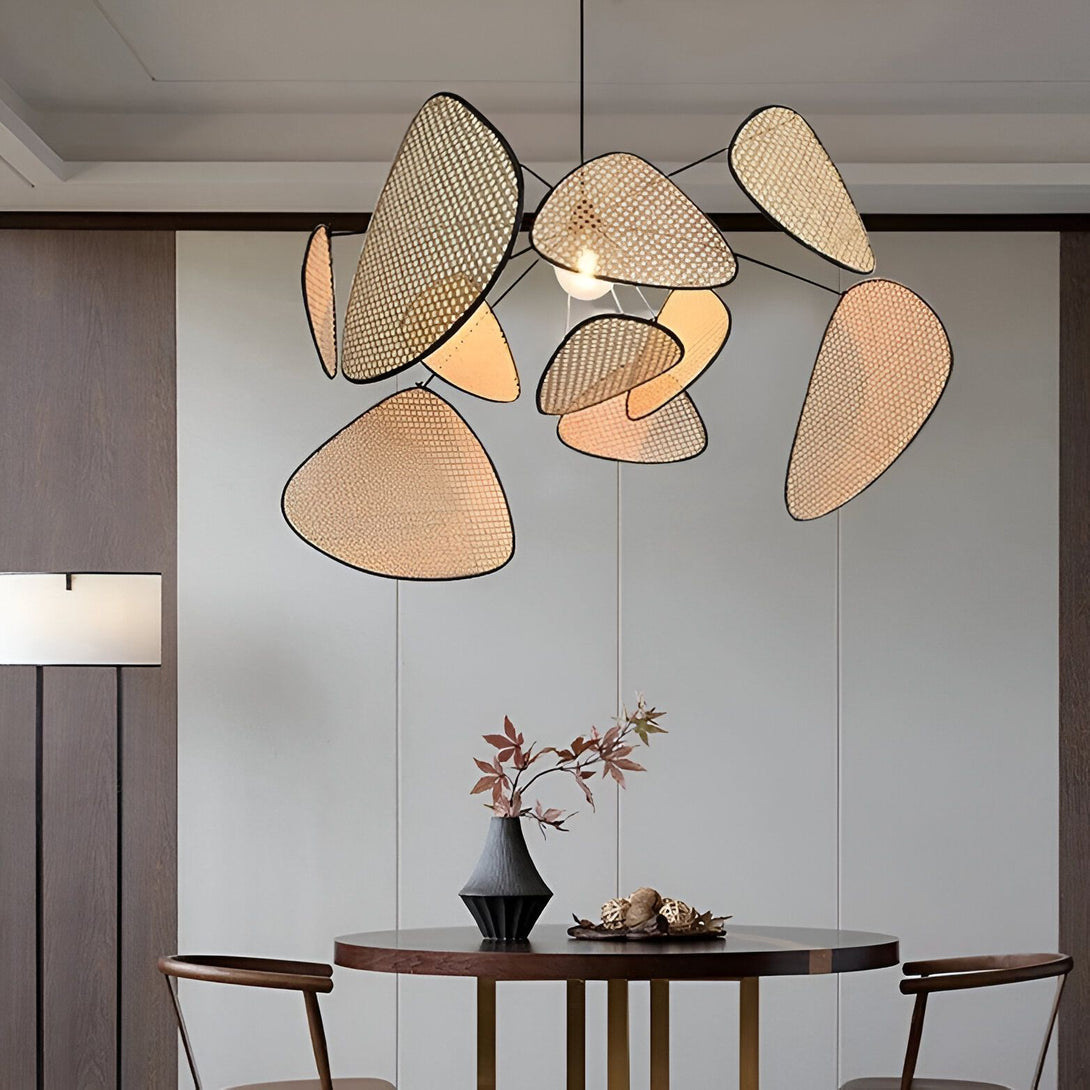 Une lampe en osier tressé en forme de pétales de fleurs est suspendue au plafond. La lampe est éclairée par une ampoule. Il y a une table en dessous avec un vase et des feuilles dessus. AY-9312322028,AY-1609755308,