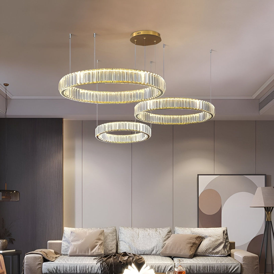 Une image d'un lustre en cristal doré à LED avec trois anneaux de différentes tailles. Le lustre est suspendu au plafond et éclairé par des lumières LED. AN-0509298699,AN-2472112572,AN-9517541910,AN-0342778935,