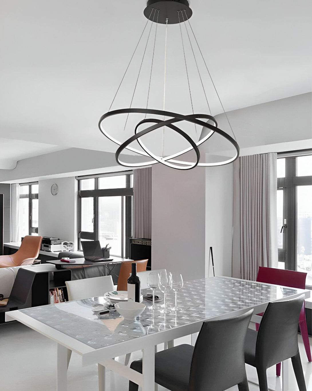 Une image d'une salle à manger avec une table en verre et des chaises noires. Il y a un lustre noir avec trois anneaux qui est suspendu au plafond. MA-1470304309,MA-2054923737,MA-2311153897,