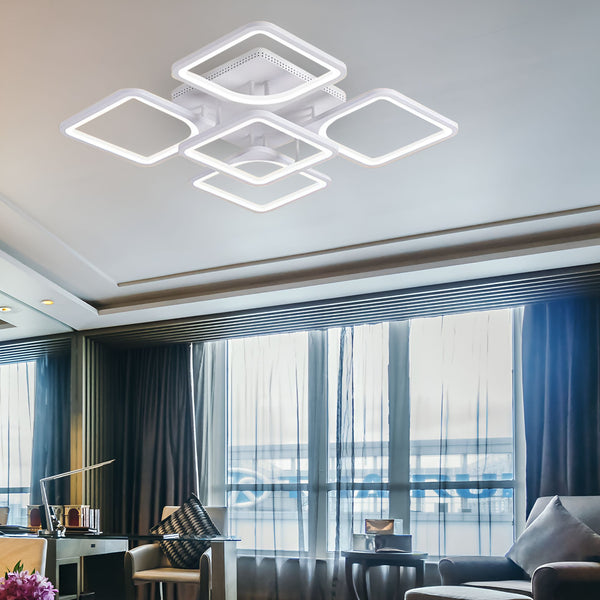 Un plafonnier LED carré blanc est fixé au plafond. Il est composé de quatre carrés lumineux et d'un carré central. Les carrés lumineux sont disposés en croix. Le plafonnier est suspendu au plafond par des câbles métalliques. LO-1375891898,LO-0522759459,