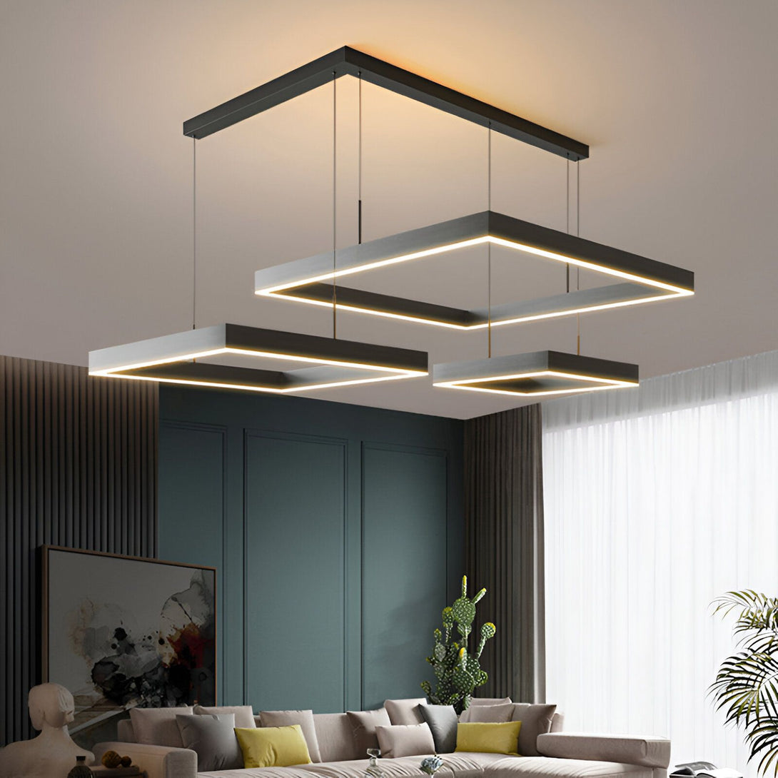 Une image d'un salon avec une suspension lumineuse noire de forme carrée. La suspension est composée de trois carrés de différentes tailles, qui sont suspendus à des câbles noirs. Les carrés sont éclairés par des LED blanches. Le salon est décoré dans un style moderne avec des murs gris et un canapé blanc. CA-4602175023,CA-4440363563,CA-3065197073,
