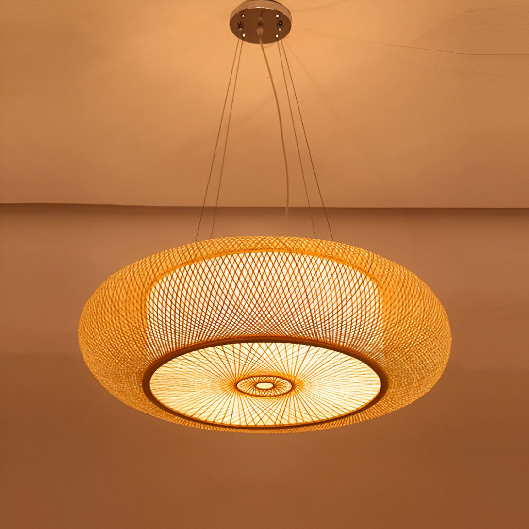 Une lampe en bambou tissé suspendue au plafond. La lampe est de forme ronde et ajourée, ce qui permet de diffuser la lumière de manière douce et tamisée. BO-0022616470,BO-2931335754,BO-5250331424,BO-6497583912,