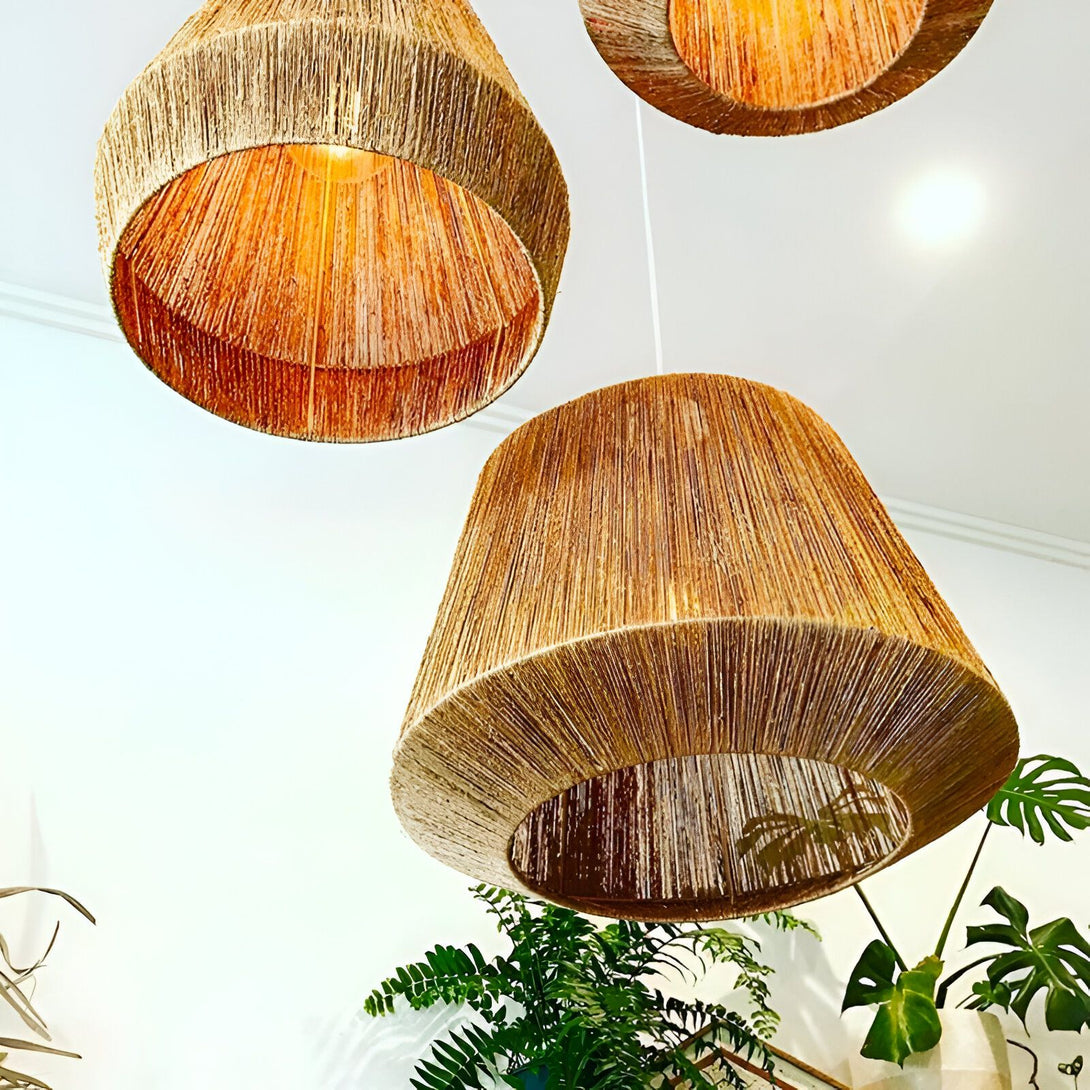 Trois lampes en corde de jute tressée sont suspendues au plafond. Les lampes sont de différentes tailles et formes, et elles émettent une lumière chaude et tamisée. Les plantes vertes en dessous ajoutent une touche de nature à la pièce. AD-6453961679,AD-6657275196,AD-8746500626,AD-6764077002,AD-2257925033,AD-5434952707,