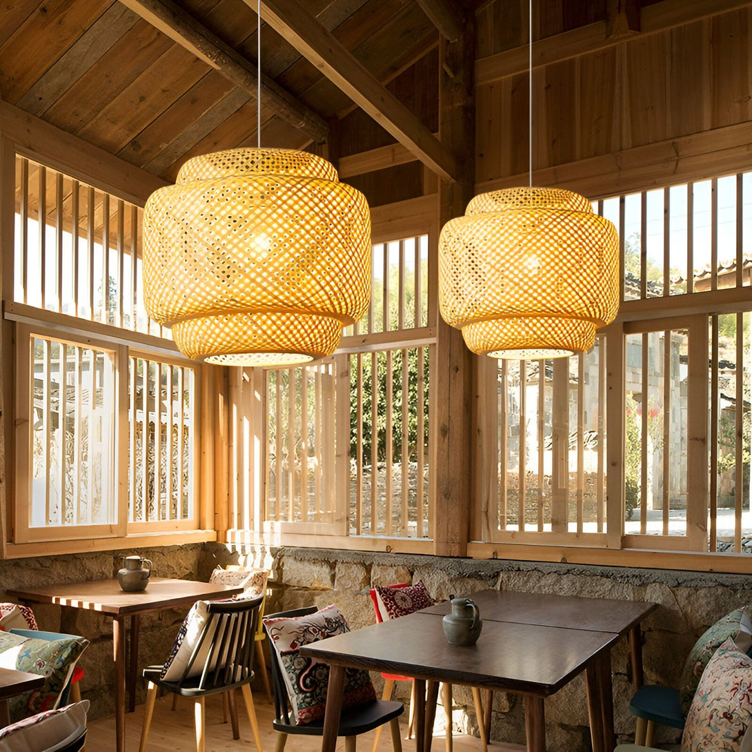 Une image de deux lampes en bambou tissé suspendues au plafond d'une pièce. Les lampes sont de forme ronde et ont une lumière chaude. La pièce est meublée de tables et de chaises en bois. EL-546763013X,EL-2418871940,