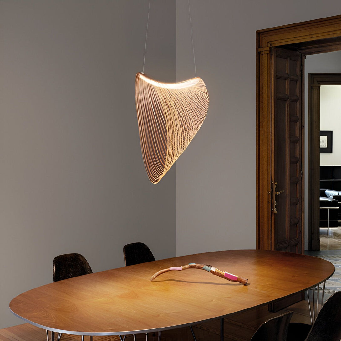 Une suspension en métal de couleur cuivre est accrochée au plafond. La suspension est en forme de vague et émet une lumière tamisée. La table en bois est éclairée par la suspension. ME-644826888X,ME-4808315661,ME-044561384X,ME-8319836859,ME-2561216225,ME-5128493199,