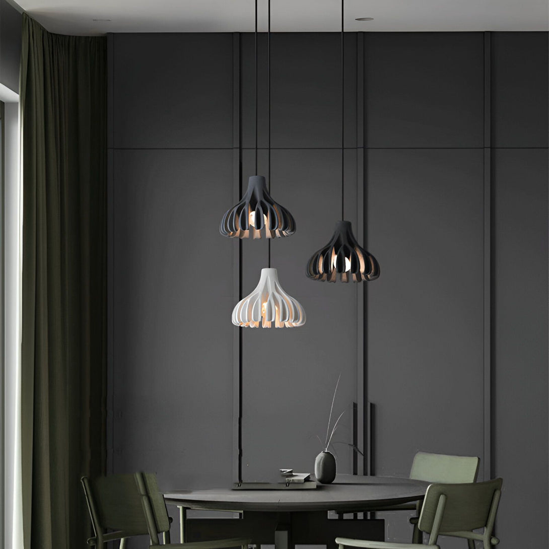 Trois suspensions noires et blanches en forme de fleur inversée au-dessus d'une table à manger ronde en bois avec des chaises vertes autour. Le tout dans une pièce aux murs gris et au sol en béton. DE-4324659125,DE-5800057117,DE-4150070571,DE-3233219504,DE-9759604302,DE-3279579503,DE-8693617931,DE-1599245205,DE-3565828951,DE-8342919889,