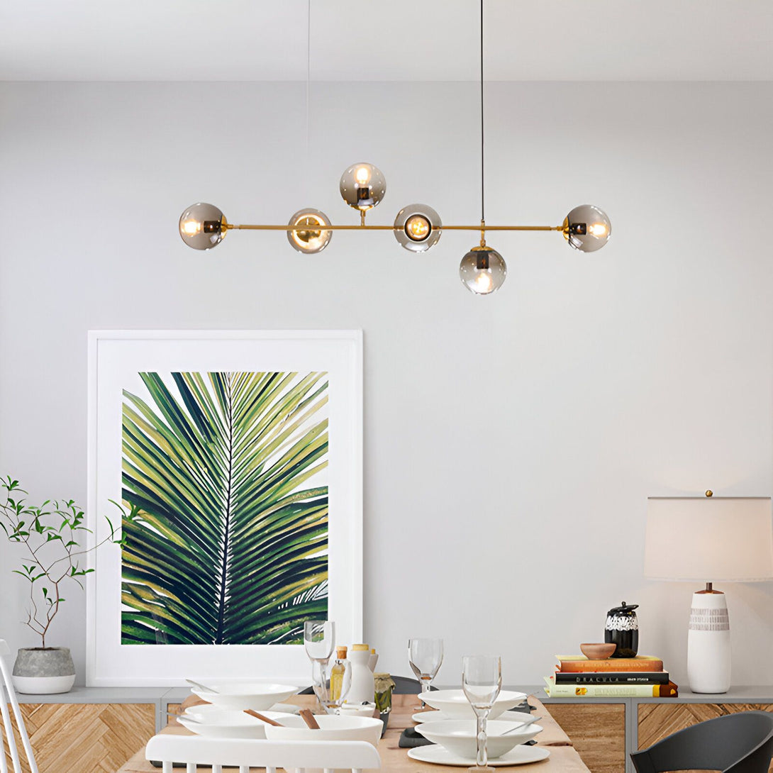 Une image d'une salle à manger avec une table en bois, des chaises blanches, un tapis vert, une plante verte, un cadre avec une image de feuilles de palmier, et un lustre doré à six branches avec des boules en verre fumé. BA-3319073257,BA-3870215909,BA-4433369764,BA-8232689269,BA-7799237627,BA-0616088558,BA-9402698388,BA-0814861172,BA-2462989250,BA-9182404453,BA-7368187922,BA-6672181431,BA-0950748706,BA-3649309513,BA-9659885725,BA-7632681620,BA-8856864762,BA-6148086980,