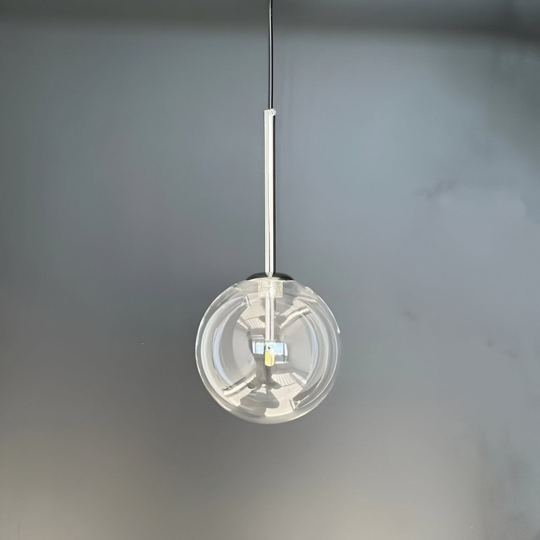 Une image d'une lampe suspendue en verre transparent avec une ampoule LED. La lampe est accrochée à un fil noir et donne une lumière blanche.