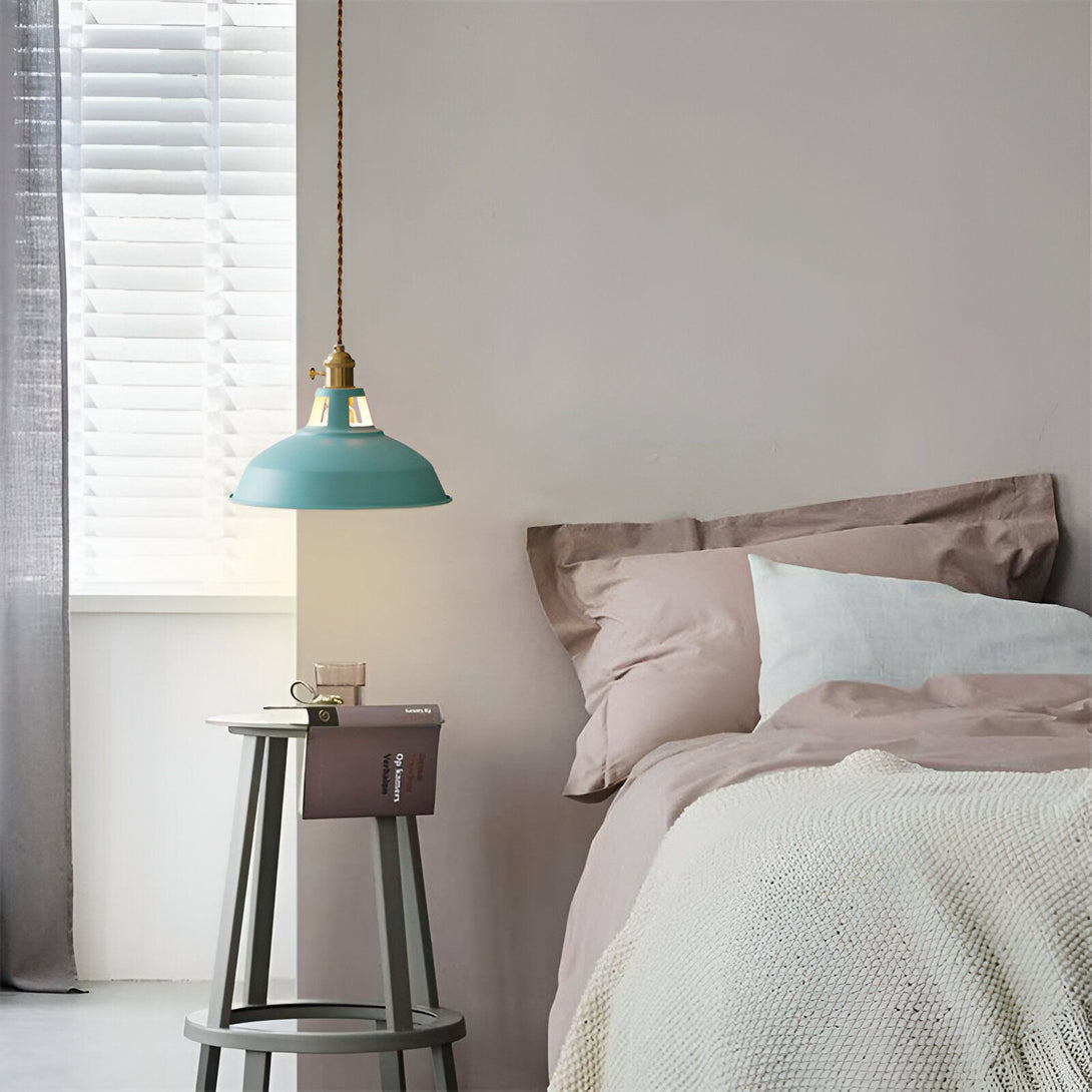 Une image d'une lampe suspendue verte au-dessus d'un tabouret en bois avec un livre ouvert dessus. À côté se trouve un lit avec des draps roses et une couverture blanche. FA-089456174X,FA-0854347186,FA-3722436486,FA-9208232328,FA-854769725X,FA-3347333489,FA-9646103529,