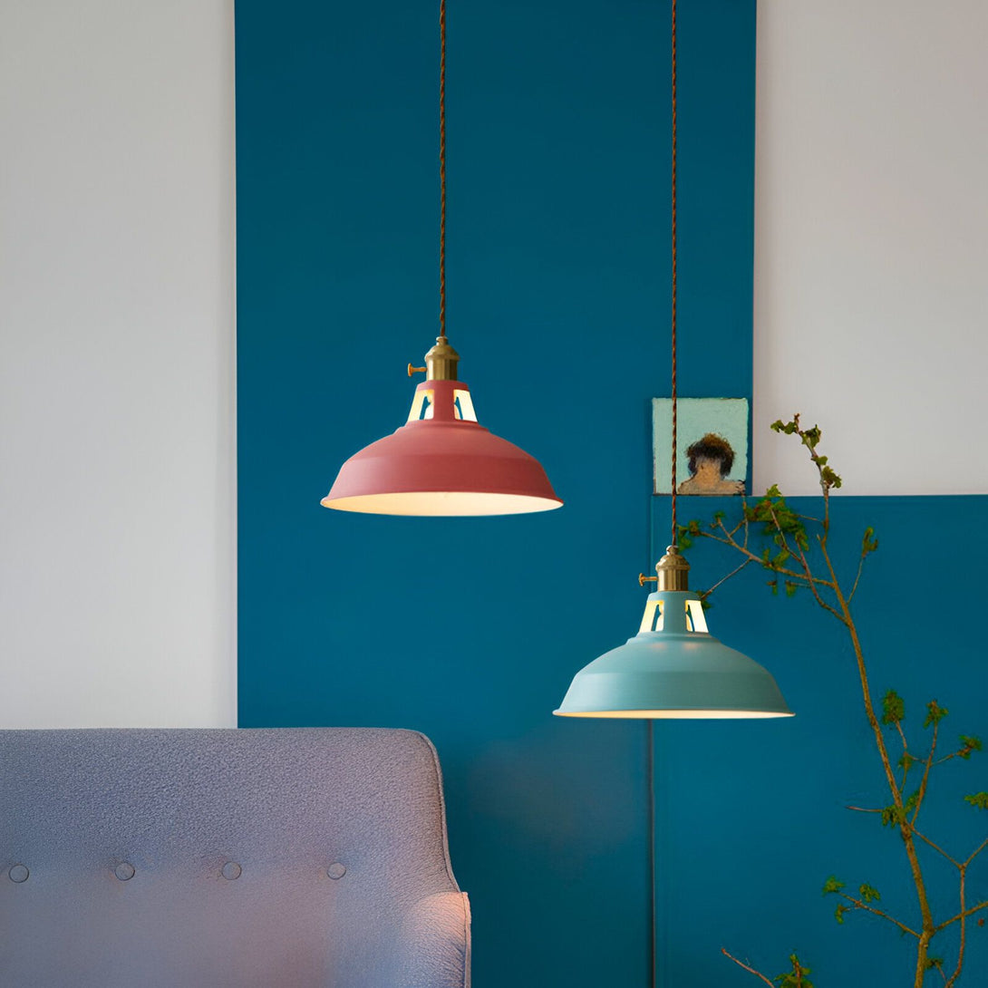 Deux suspensions en métal coloré, l'une rose et l'autre verte, sont accrochées au plafond. Le fond est un mur bleu foncé avec des lignes blanches. Il y a un canapé gris à gauche de l'image. FA-089456174X,FA-0854347186,FA-3722436486,FA-9208232328,FA-854769725X,FA-3347333489,FA-9646103529,