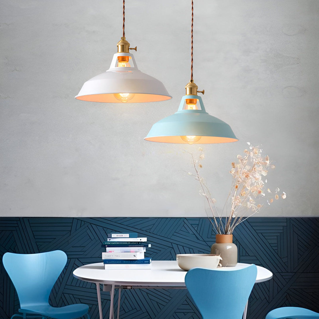 Deux suspensions en métal blanc et bleu pastel sont accrochées au plafond. Elles sont toutes les deux munies d'une ampoule à filament. En dessous, se trouve une table ronde en bois avec des chaises bleues. FA-089456174X,FA-0854347186,FA-3722436486,FA-9208232328,FA-854769725X,FA-3347333489,FA-9646103529,