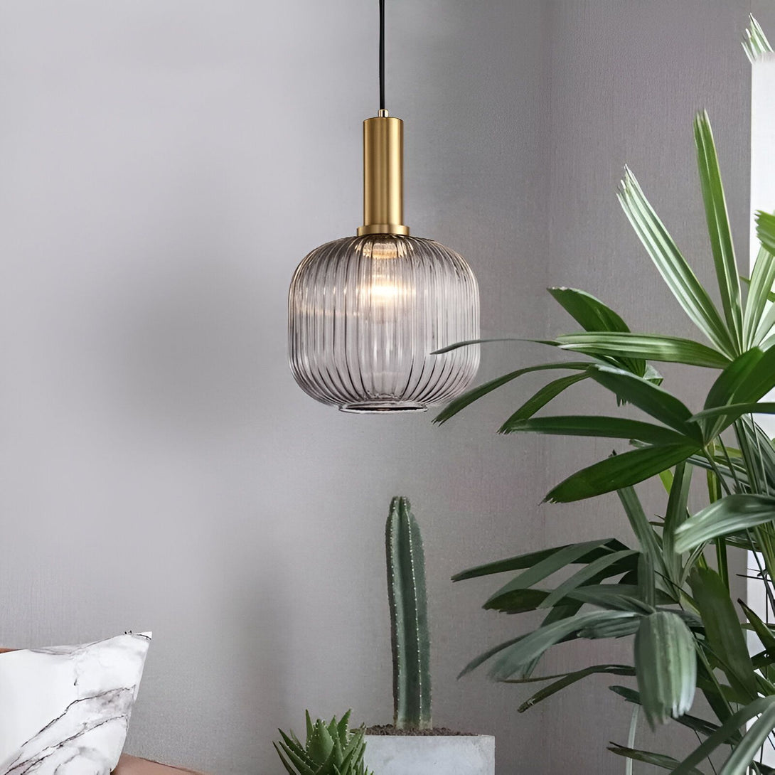 Une lampe en verre gris avec des reflets dorés est suspendue au plafond. La lampe est de forme ronde et a un design moderne. Elle est entourée de plantes vertes. LI-8529220781,LI-4720739318,LI-9433830652,LI-6287765305,