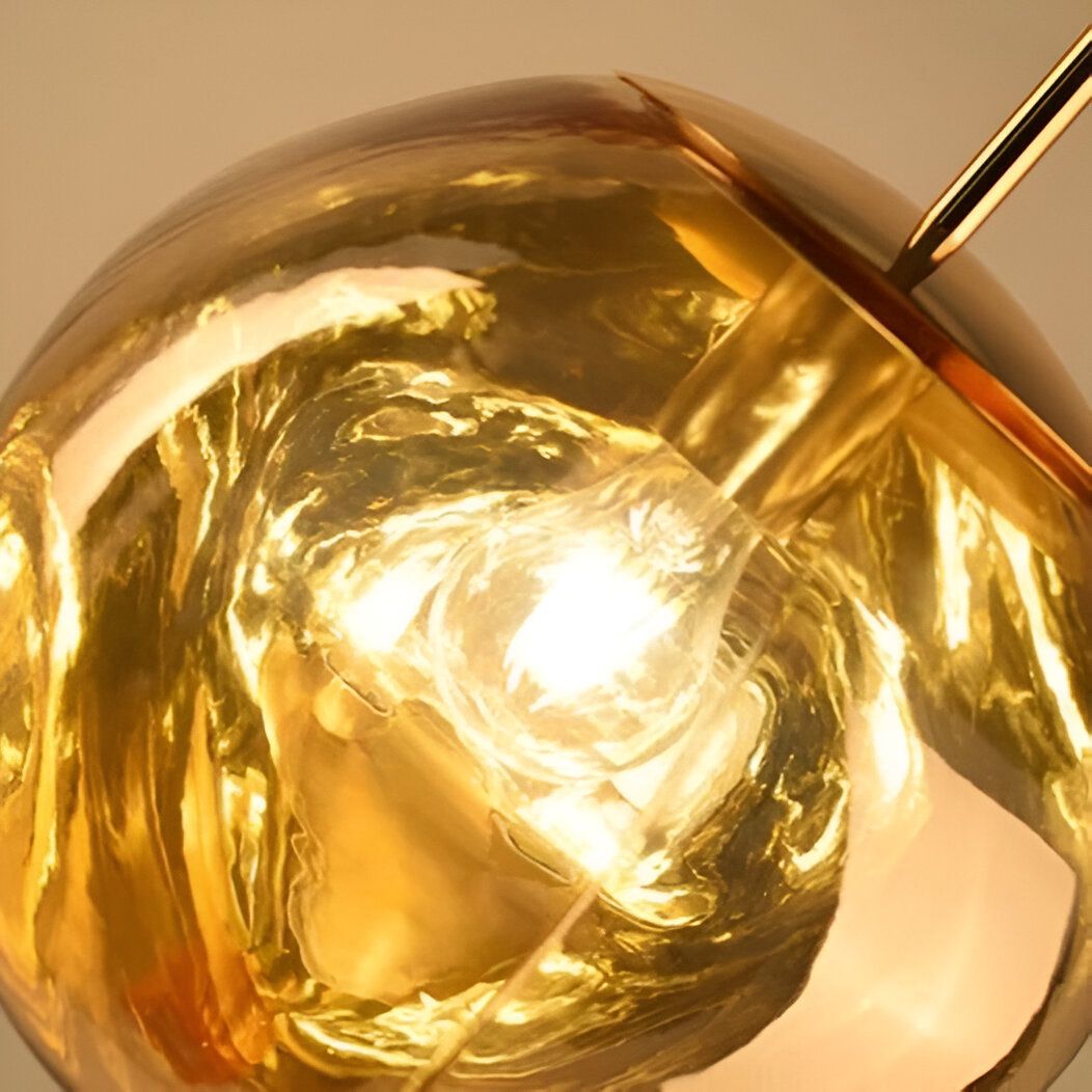 Une sphère dorée en verre soufflé est suspendue à un fil doré. La lumière est allumée à l'intérieur de la sphère, ce qui crée un effet de halo doré. LA-8821800008,LA-2444977270,LA-6285199337,LA-272961009X,LA-427140456X,LA-929285948X,LA-4420956534,LA-5212907888,LA-5689243493,