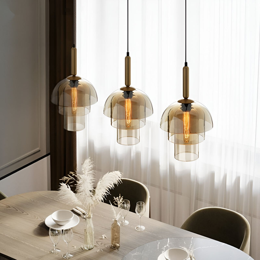 Une image de trois suspensions en verre fumé avec des ampoules à filament. Les suspensions sont accrochées au plafond par des fils noirs. Il y a une table en bois avec des chaises autour. Sur la table, il y a une bouteille en verre, des verres à vin et des assiettes. LA-8544977014,LA-4041186528,