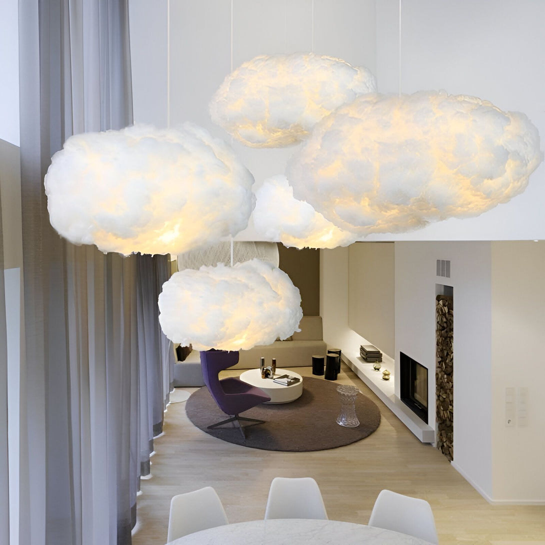 Quatre lampes en forme de nuage sont suspendues au plafond d'un salon. Les nuages sont blancs et diffusent une lumière douce. Le sol est en bois clair et les murs sont blancs. Il y a une cheminée dans le coin du salon et une table basse avec des chaises autour. CL-0076737969,CL-3719537056,CL-8704886801,