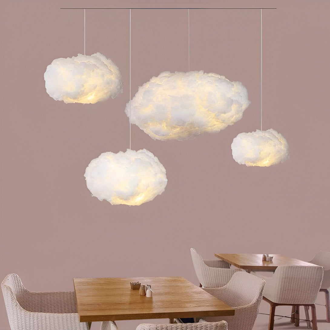 Quatre lampes en forme de nuage sont suspendues au plafond. Les nuages sont blancs et ont l'air doux et moelleux. Les lampes sont allumées et émettent une lumière douce et diffuse. Il y a des tables et des chaises en dessous des lampes. CL-0076737969,CL-3719537056,CL-8704886801,